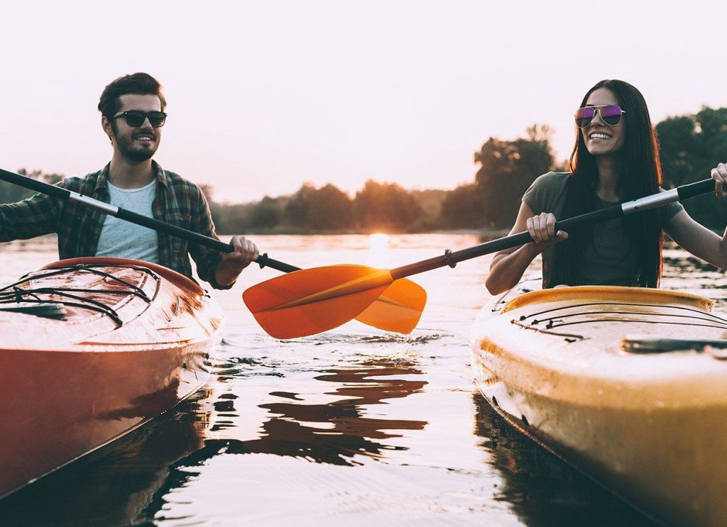 Two people kayaking on a serene lake at sunset, enjoying outdoor adventure and nature exploration