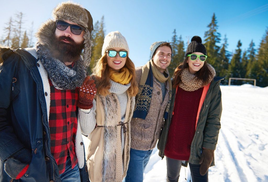 Friends enjoying a sunny winter day, wearing cosy clothes and sunglasses in a snowy forest setting